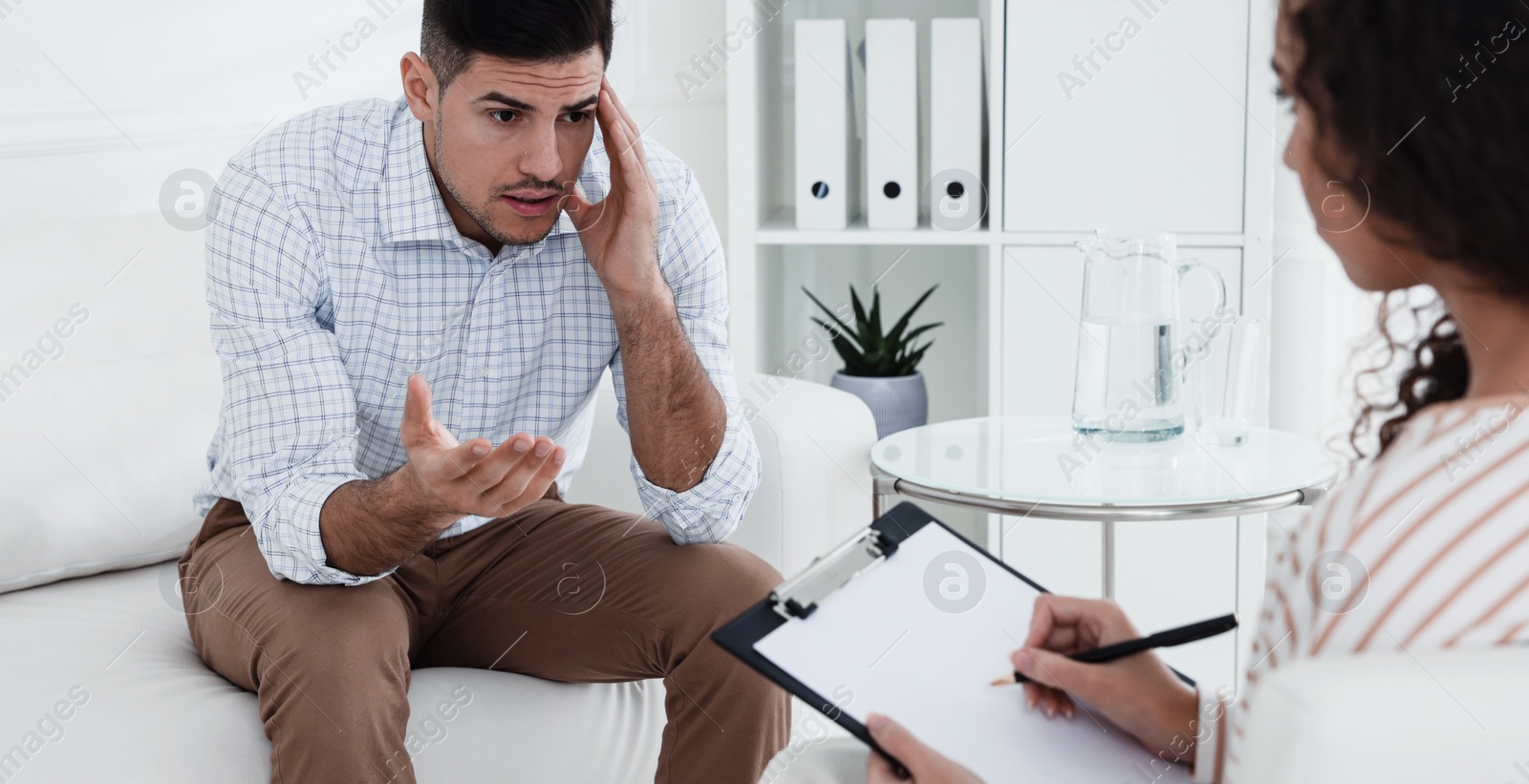 Image of Unhappy man having session with his therapist indoors. Banner design