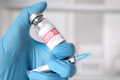 Photo of Doctor with coronavirus vaccine and syringe in laboratory, closeup