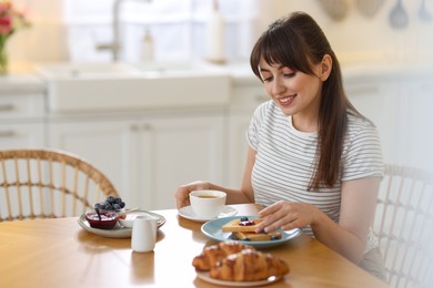 Photo of Smiling woman eating tasty breakfast at table indoors