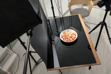 Photo of Professional equipment and salad with prosciutto on table in photo studio. Food photography