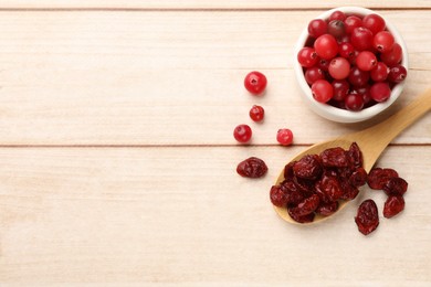 Photo of Spoon with dried cranberries and fresh berries in bowl on wooden table, flat lay. Space for text