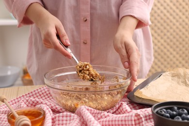 Photo of Woman making granola at table in kitchen, closeup