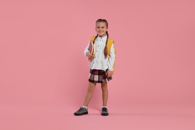 Photo of Happy schoolgirl with backpack and books on pink background