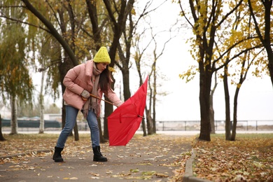 Woman with red umbrella caught in gust of wind outdoors