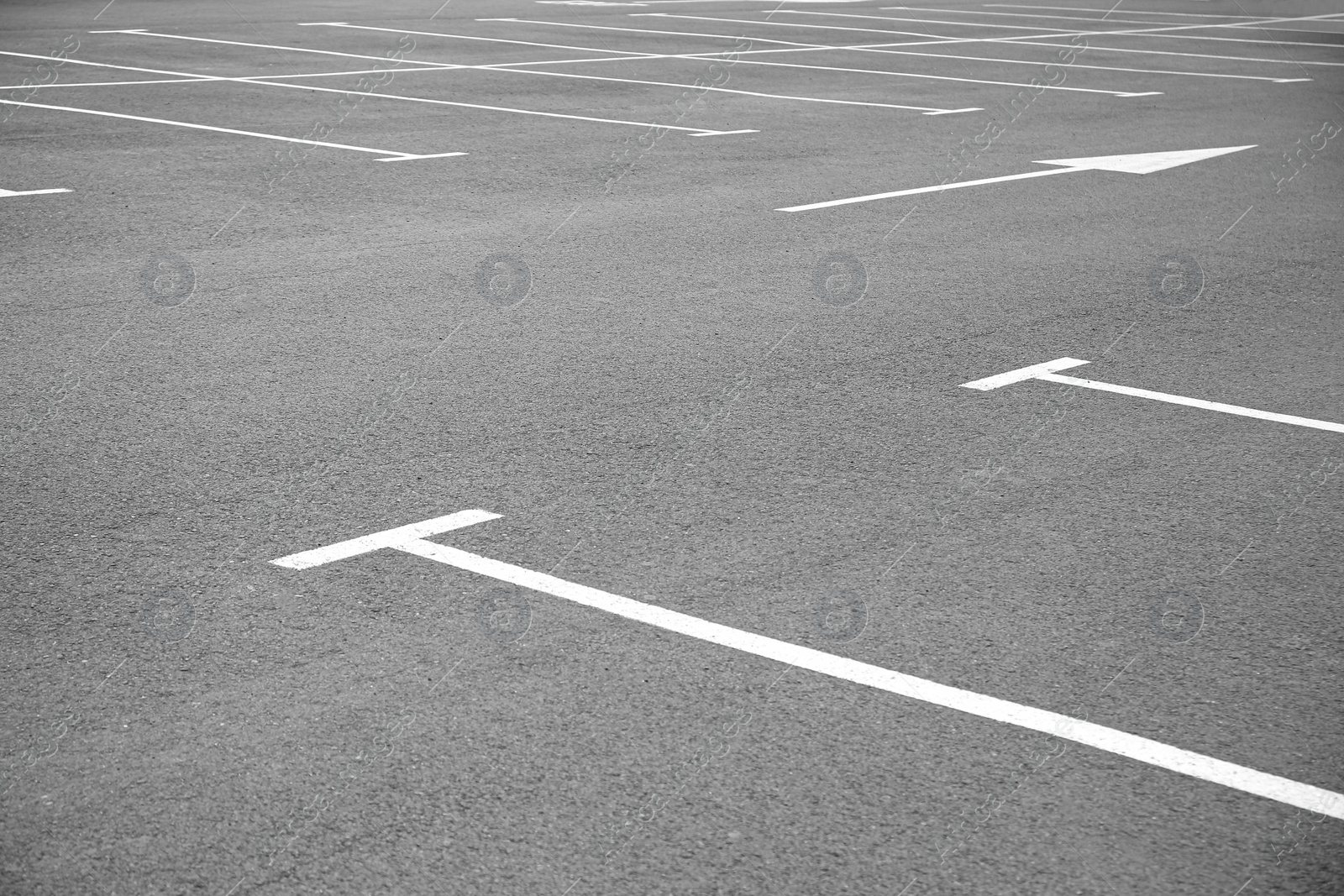 Photo of White painted car parking lots and arrow marking on asphalt outdoors