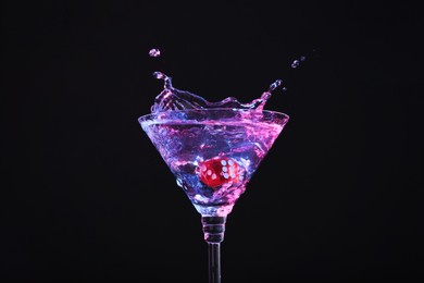 Photo of Casino dice falling into glass of alcohol drink on black background