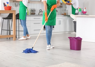 Photo of Woman cleaning floor with mop in kitchen, closeup