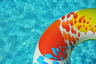 Photo of Colorful inflatable ring floating in swimming pool on sunny day, above view. Space for text