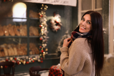 Photo of Beautiful woman in decorated cafe, space for text. Christmas celebration