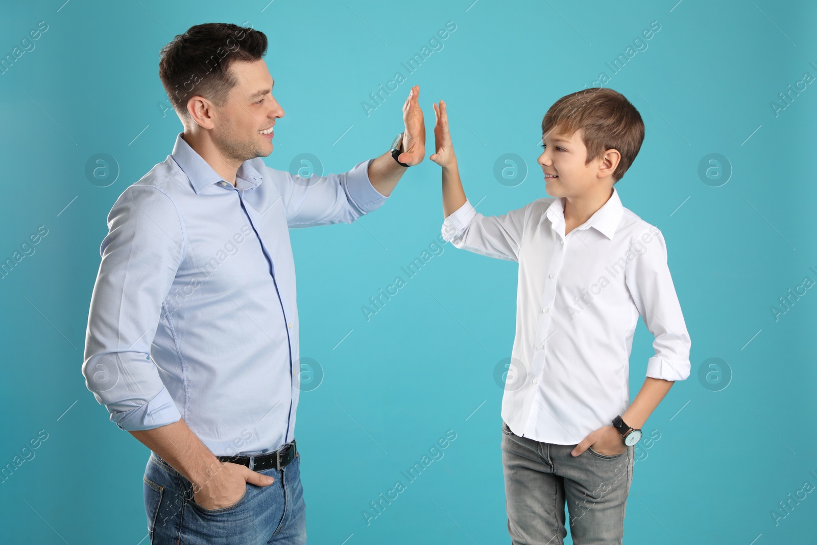 Photo of Portrait of dad and his son giving high five on color background