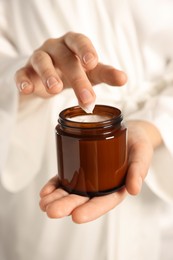 Photo of Woman holding jar of hand cream, closeup