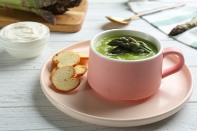 Photo of Delicious asparagus soup served on white wooden table