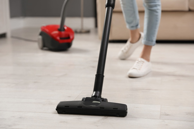 Photo of Young woman using vacuum cleaner at home, closeup
