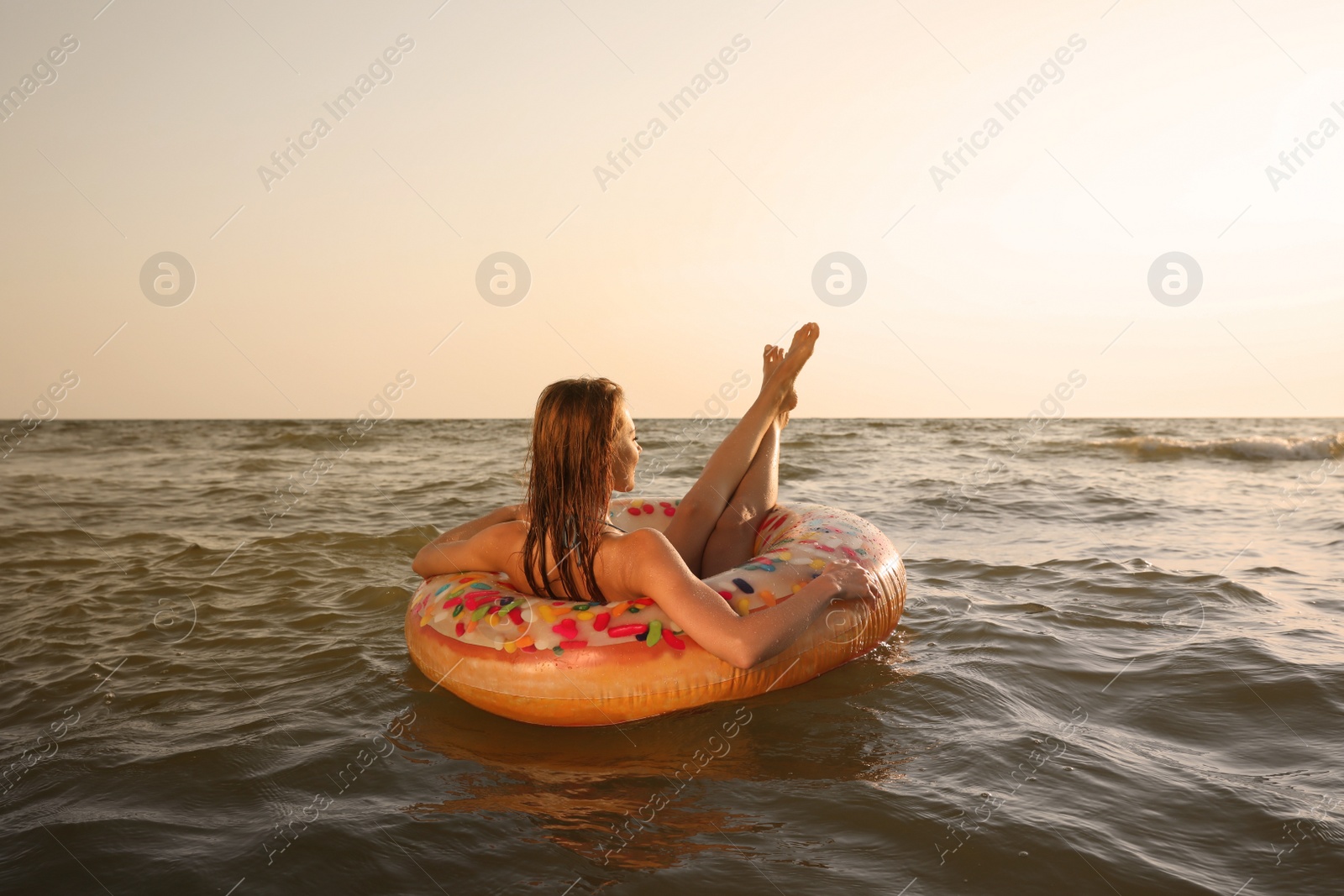Photo of Woman with inflatable ring resting in sea, back view