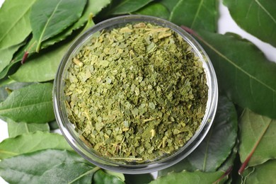 Photo of Bowl with fresh and ground bay leaves on white background, top view