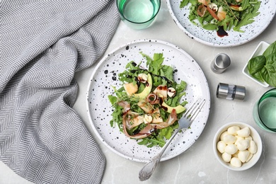 Photo of Plate of salad with melon slices and prosciutto on gray table, flat lay