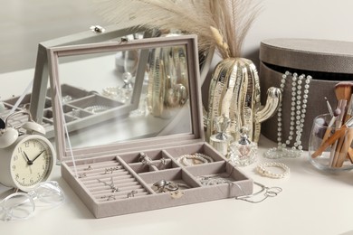 Photo of Jewelry boxes with many different accessories, perfumes, alarm clock and decor on white table