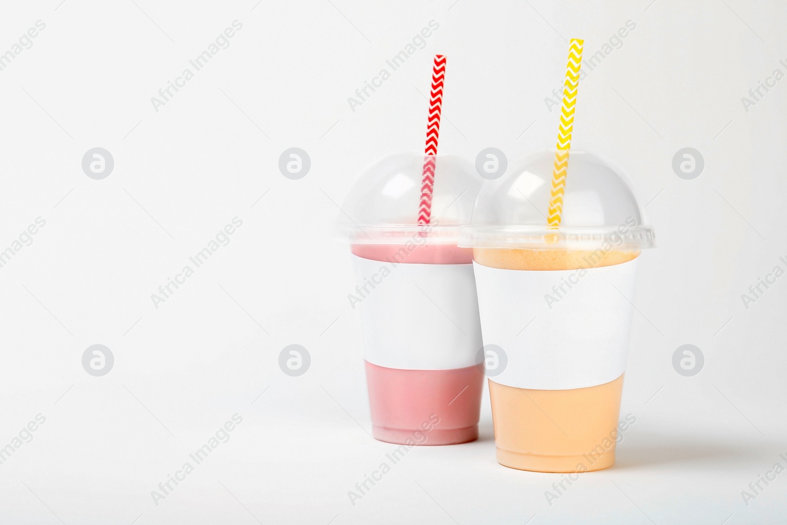 Photo of Plastic cups with delicious milk shakes on white background