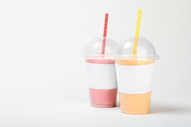 Plastic cups with delicious milk shakes on white background