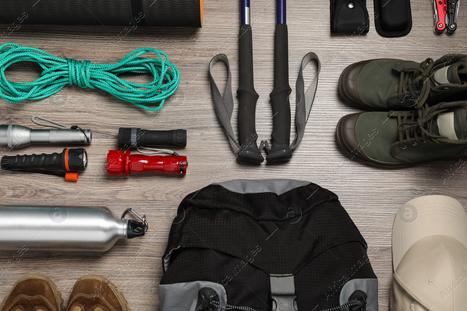 Photo of Flat lay composition with trekking poles and other hiking equipment on wooden background