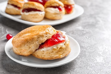 Photo of Tasty scone with clotted cream and jam on table, closeup