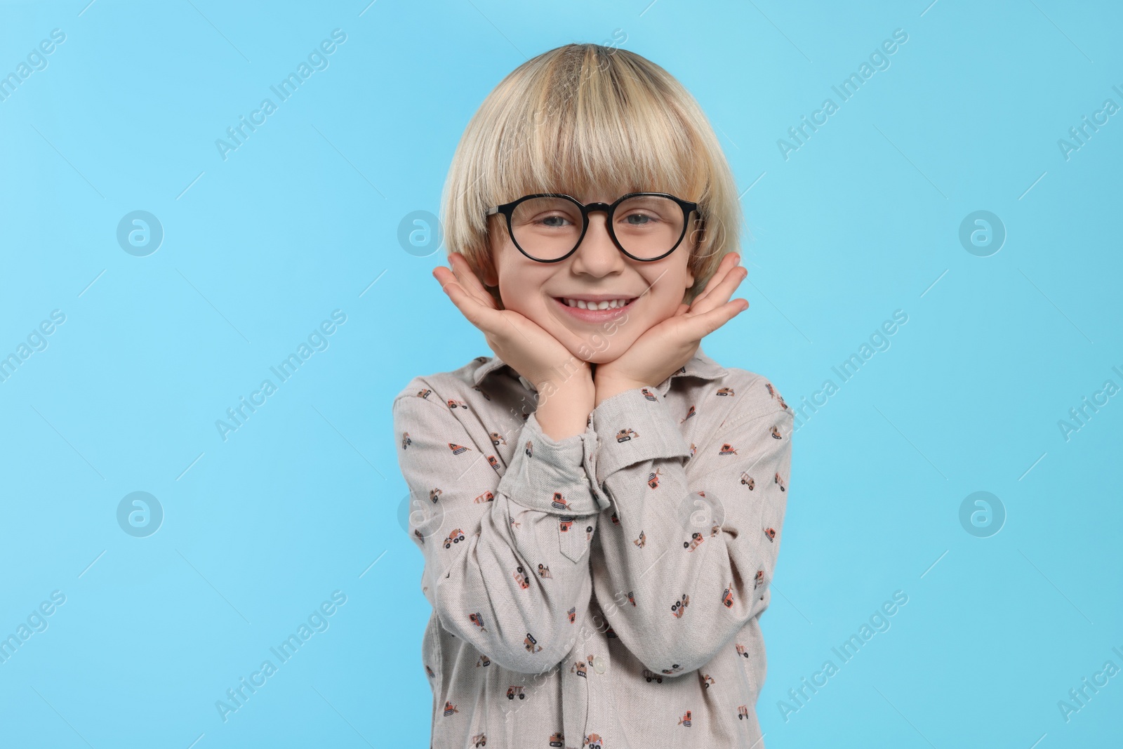 Photo of Cute little boy wearing glasses on light blue background