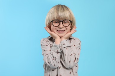 Photo of Cute little boy wearing glasses on light blue background