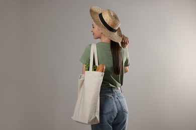 Woman with eco bag full of products on light background