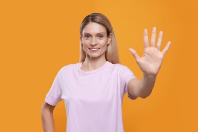 Photo of Woman giving high five on orange background