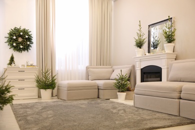 Photo of Stylish living room interior with little fir trees and Christmas decorations