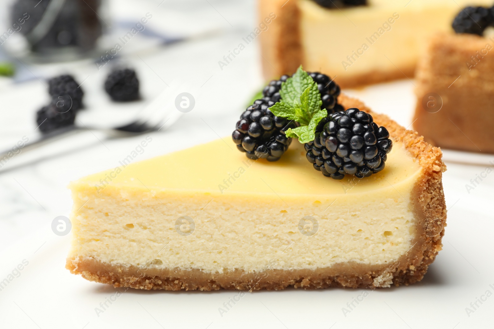 Photo of Piece of delicious cheesecake decorated with blackberries on table