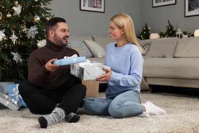 Photo of Happy couple exchanging Christmas gifts at home