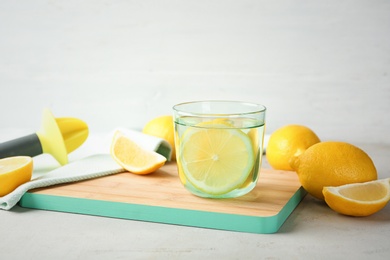 Glass of water with lemon slice on wooden board