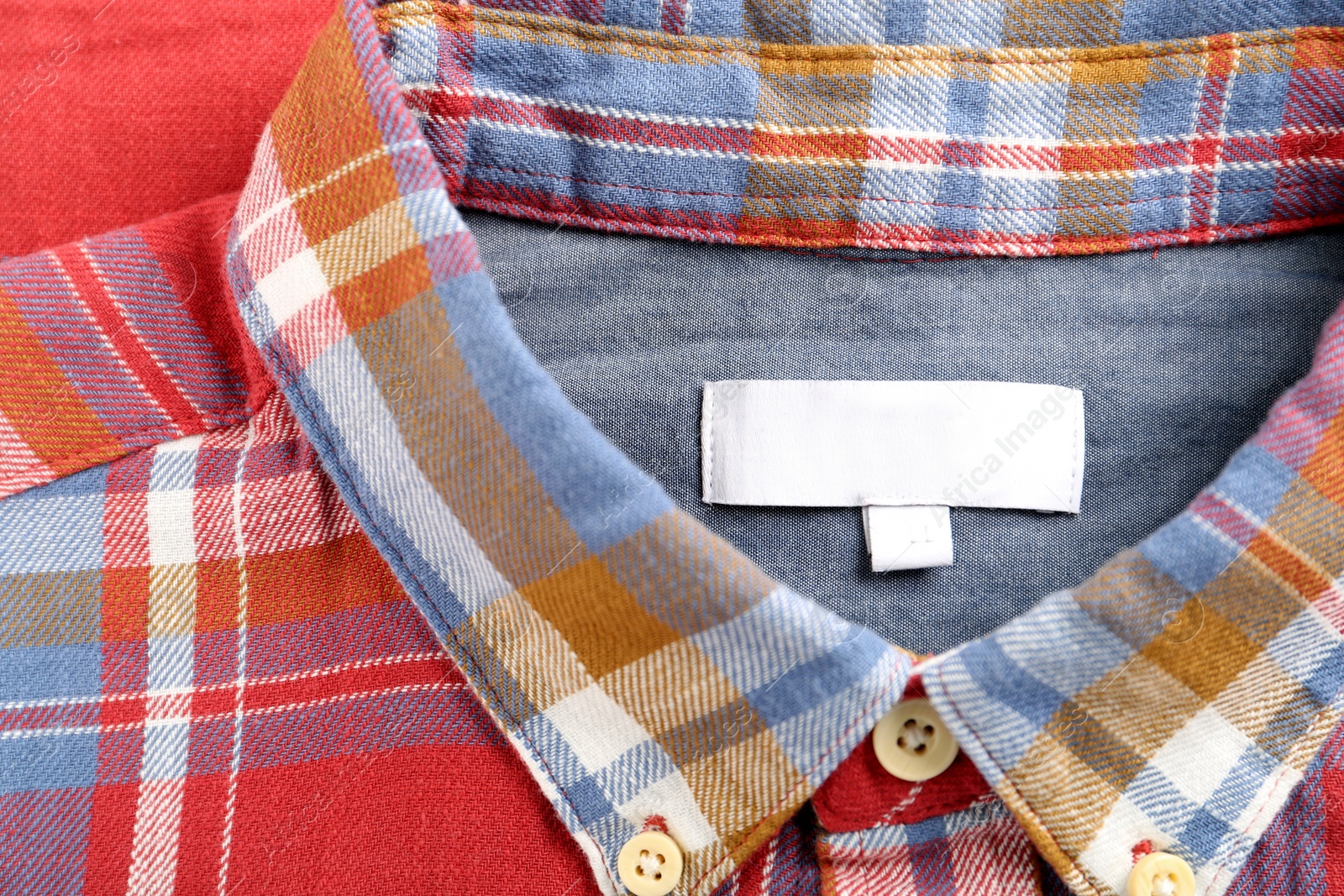 Photo of Blank clothing label on checkered shirt, top view