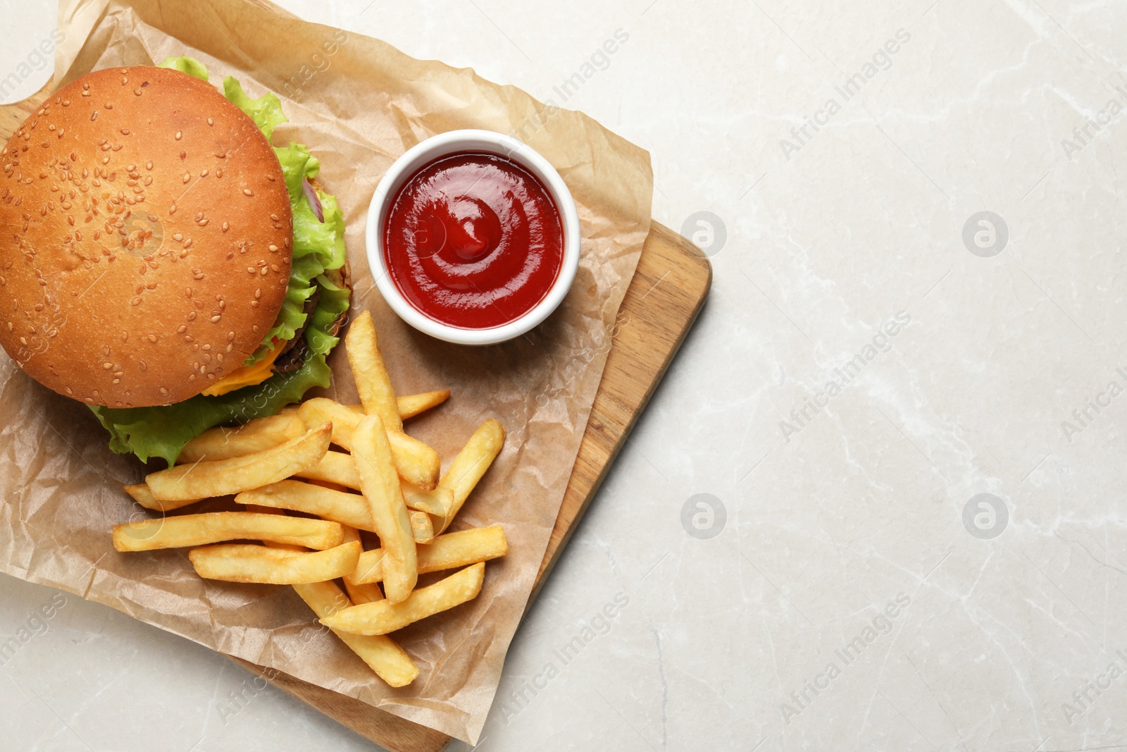 Photo of French fries, tasty burger and sauce on white marble table, top view. Space for text