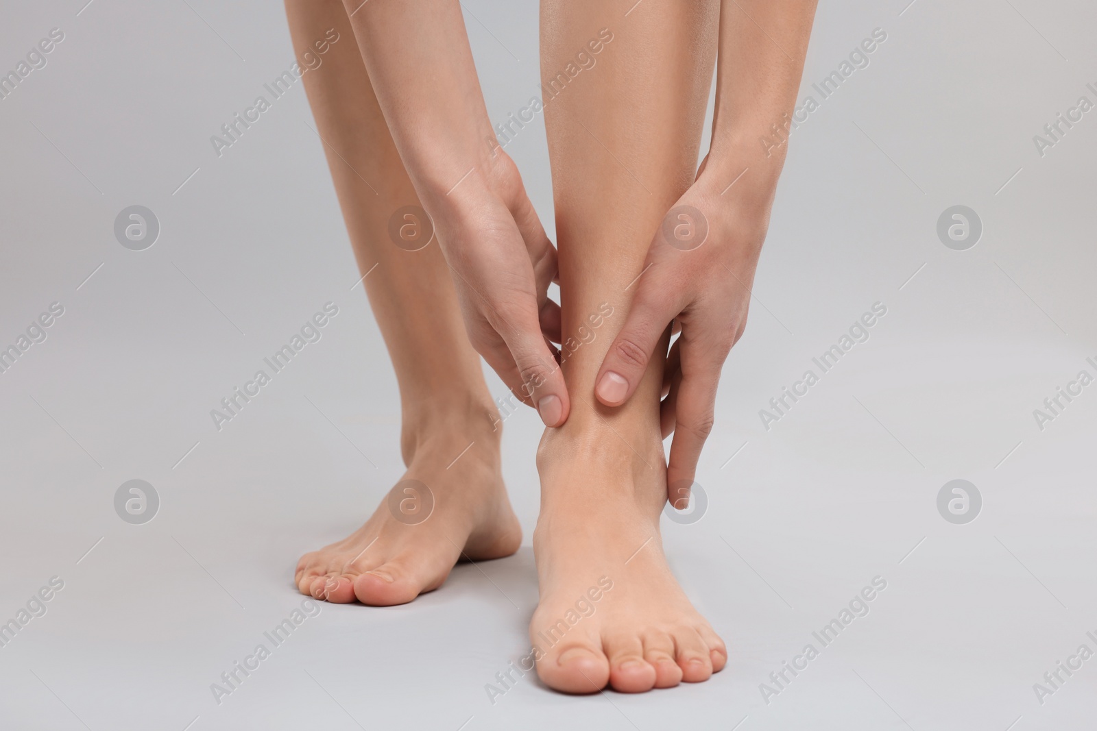 Photo of Woman suffering from leg pain on grey background, closeup