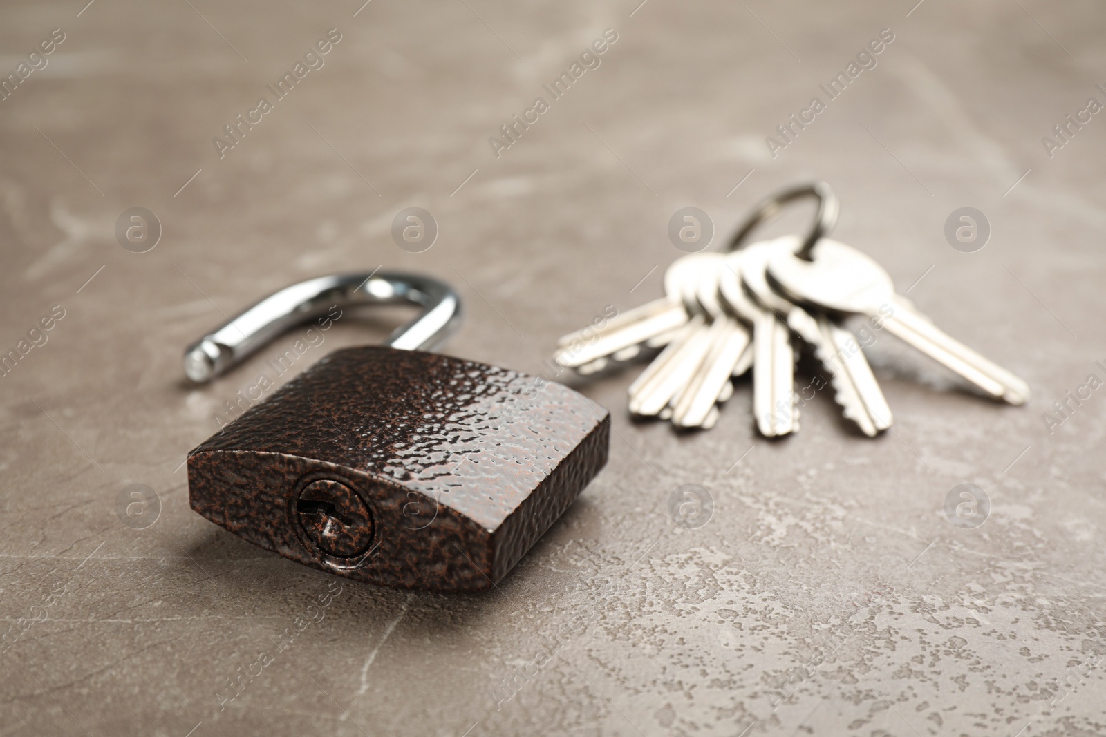Photo of Modern padlock and keys on grey marble table, closeup