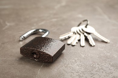 Modern padlock and keys on grey marble table, closeup