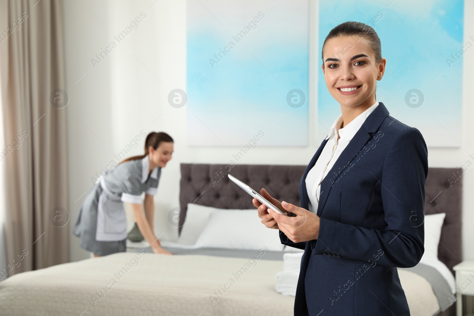 Photo of Housekeeping manager with tablet checking maid work in hotel room. Space for text