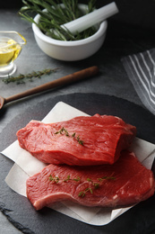 Photo of Fresh raw beef cut with thyme on grey table