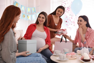 Happy pregnant woman spending time with friends at baby shower party