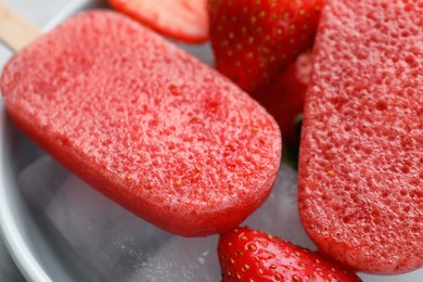 Photo of Tasty strawberry ice pops in bowl, closeup. Fruit popsicle