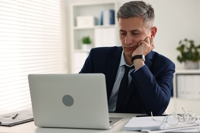 Photo of Sleepy man at table with laptop in office