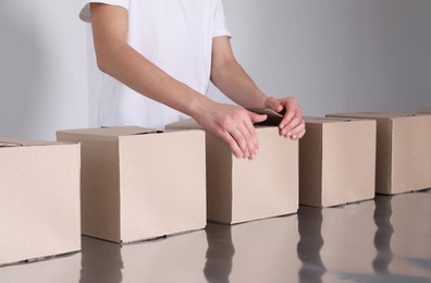 Photo of Man folding cardboard boxes at table, closeup. Production line