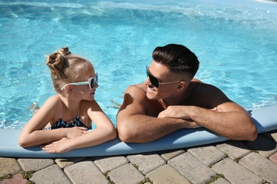 Photo of Happy man and his daughter in outdoor swimming pool on sunny summer day