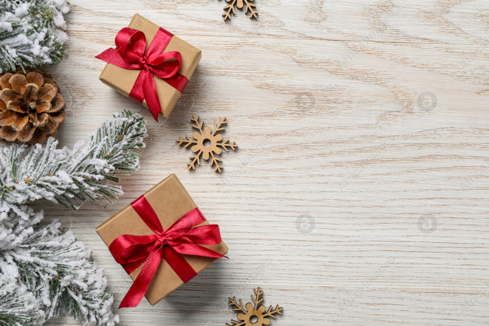 Photo of Gift boxes, fir tree branches and Christmas decor on white wooden table, flat lay. Space for text