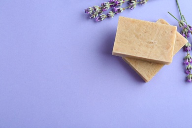 Photo of Hand made soap bars with lavender flowers on violet background, flat lay. Space for text