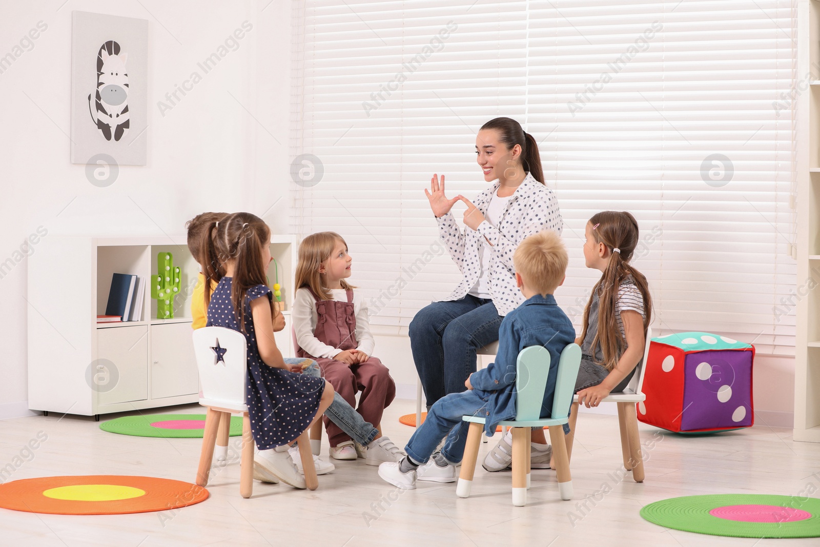 Photo of Nursery teacher and group of cute little children learning numbers in kindergarten. Playtime activities