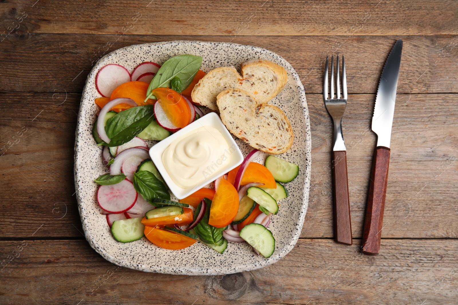 Photo of Plate of delicious vegetable salad with mayonnaise and croutons served on wooden table, flat lay