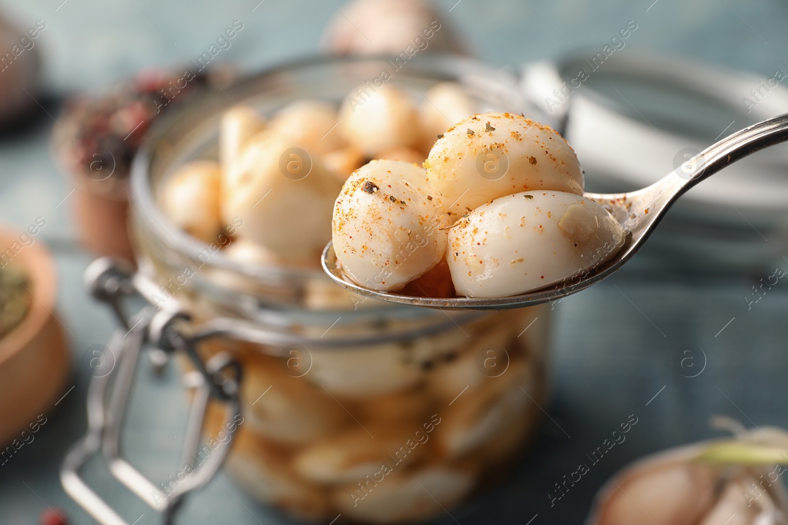 Photo of Preserved garlic in spoon over table, closeup. Space for text